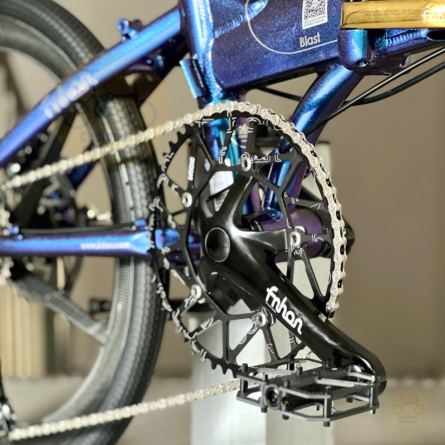Close-up of a bicycle crankset with a black chainring and crank arm branded 'fnbn', attached to a blue bicycle frame.