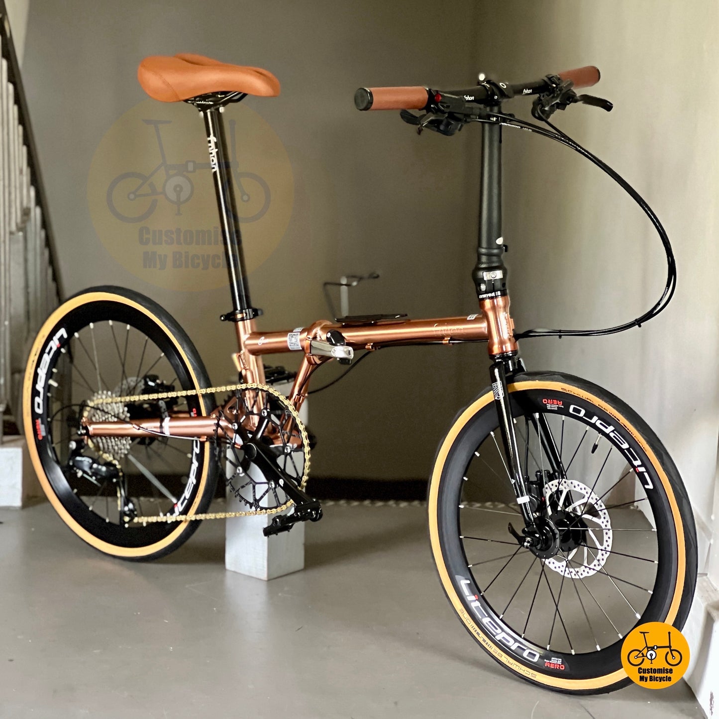 7. Close-up of titanium gold Fnhon Gust 22” foldie on wooden platform, sunlight reflecting off the polished frame.
