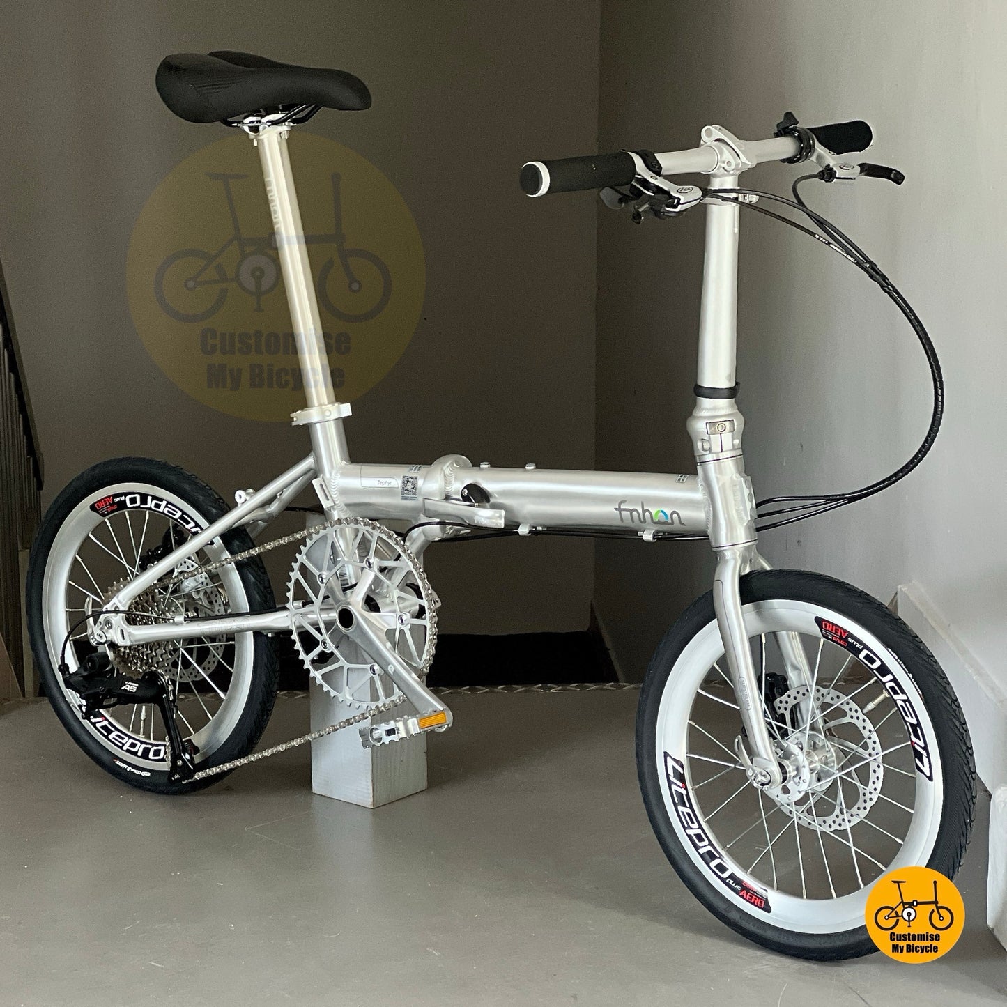 Angled view of Fnhon Zephyr polished silver folding bicycle, emphasizing smooth frame curves and sunset lighting effect.